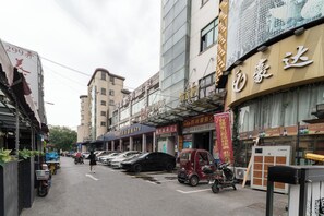 A street with parked cars, a red three-wheeled vehicle, and various storefronts with signage. - CaptainNo 5YouthHotel XianxiaRoad Branch (Shanghai)