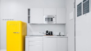 A compact kitchen with white cabinets, a stainless steel microwave, a yellow refrigerator, and a coffee maker on the counter. - Easylife -Modern and elegant in the heart of Milan (Milano)