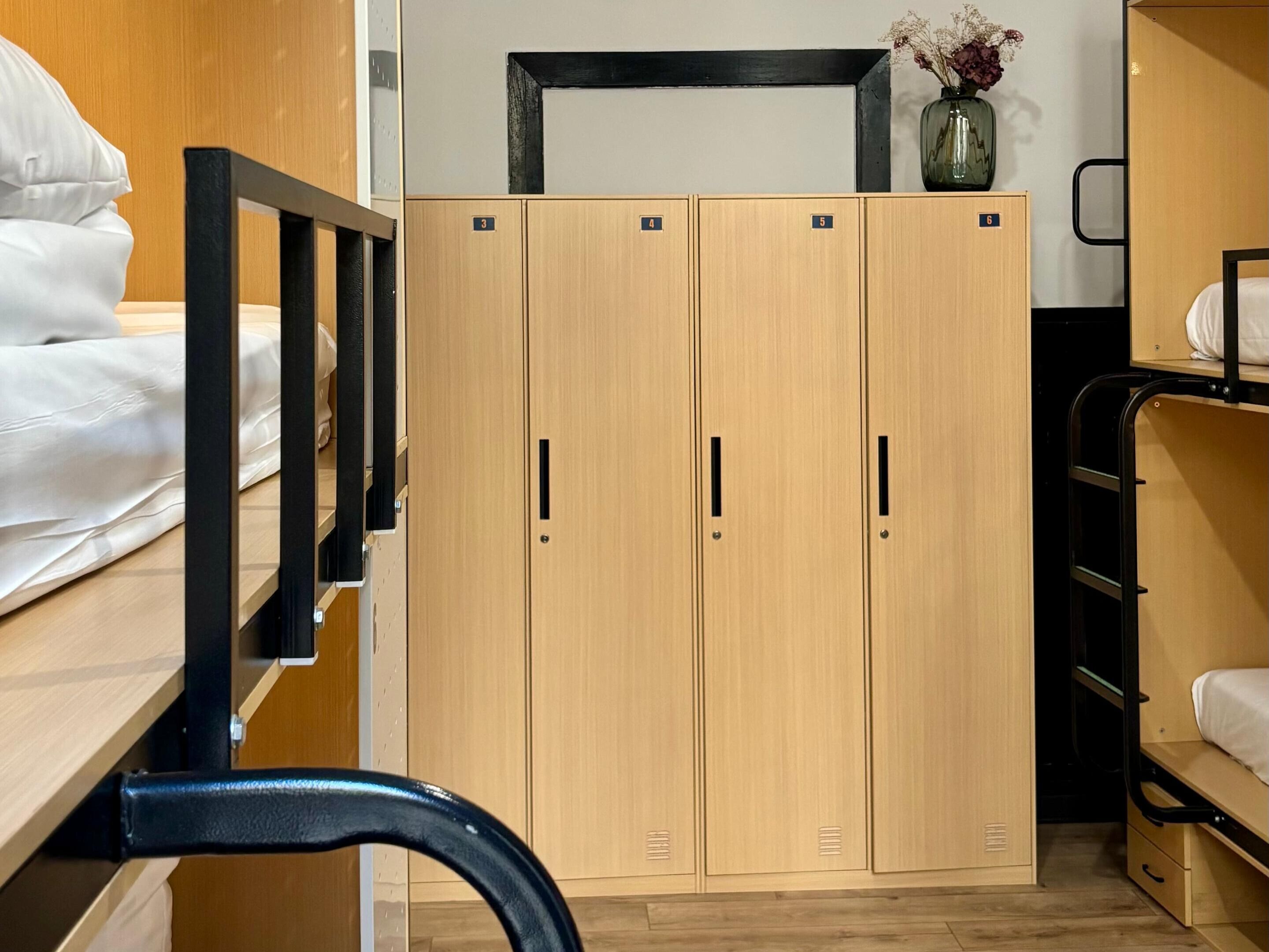 Un dormitorio con literas, armarios de madera y una mesita con un florero.