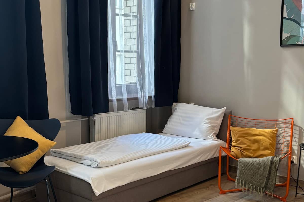 A compact room with a single bed, a small table, and a chair.