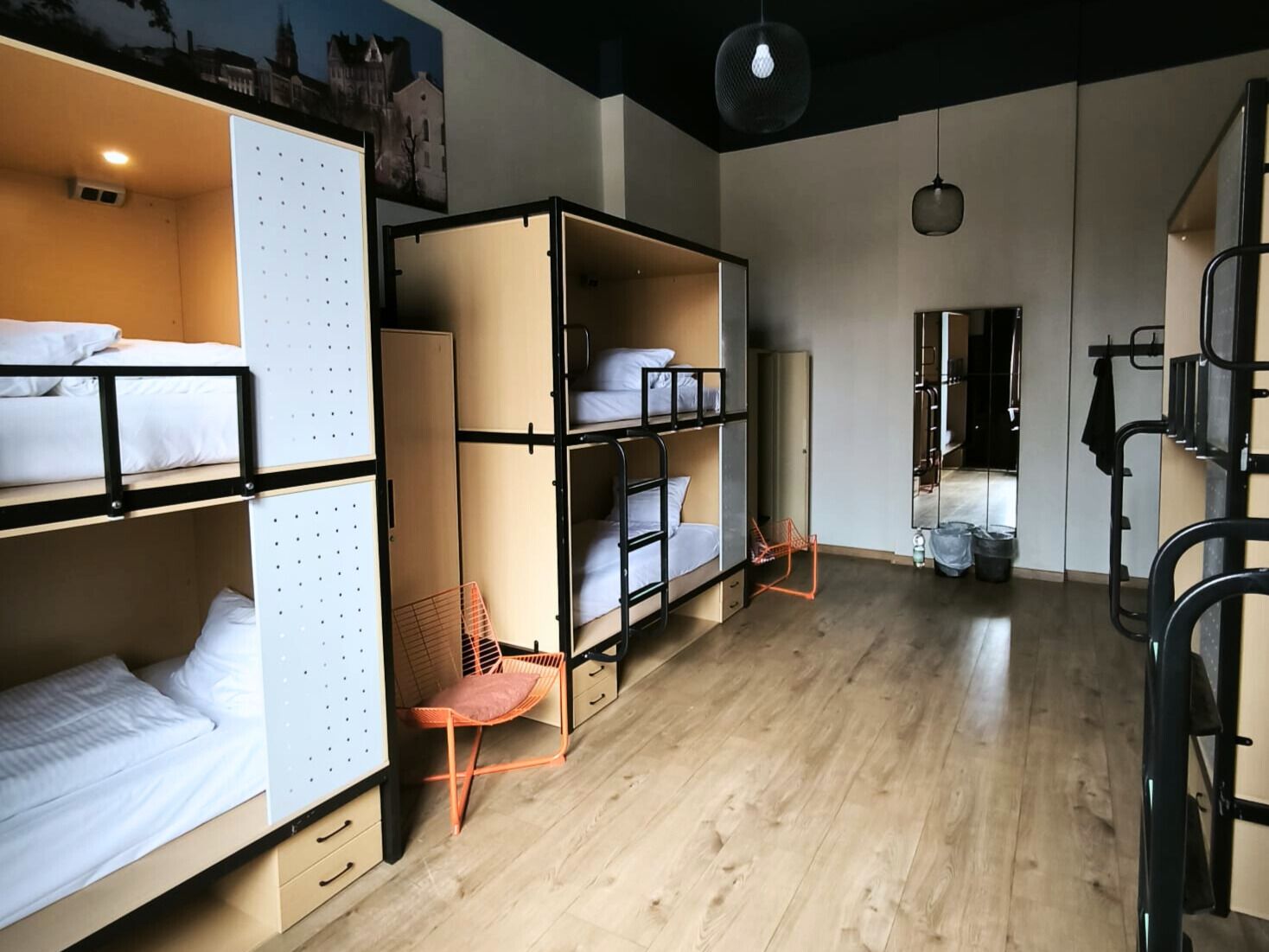 Habitación tipo dormitorio con literas, una silla y un espejo.