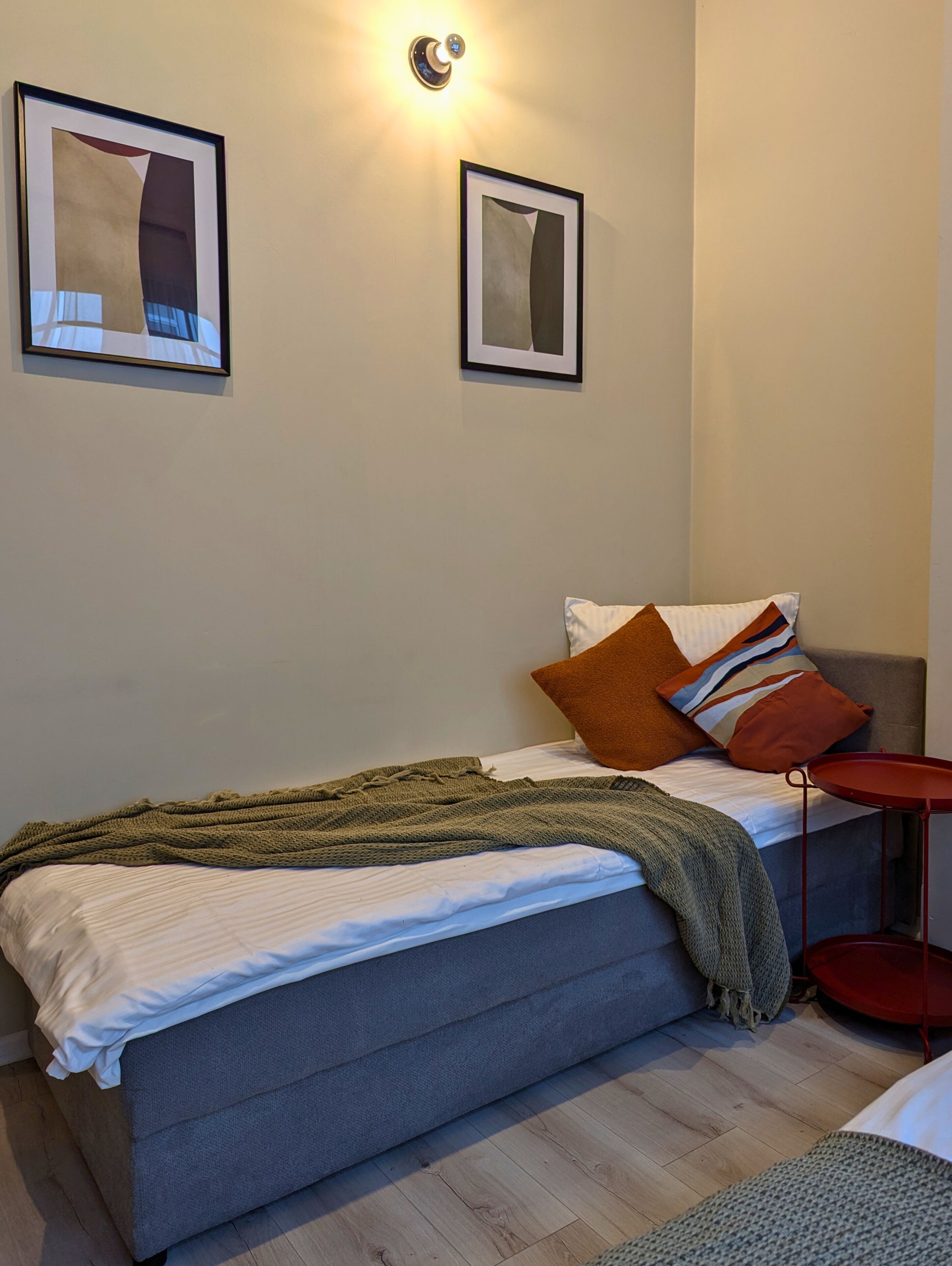 A neatly arranged bedroom with a bed, pillows, a blanket, and a small side table.
