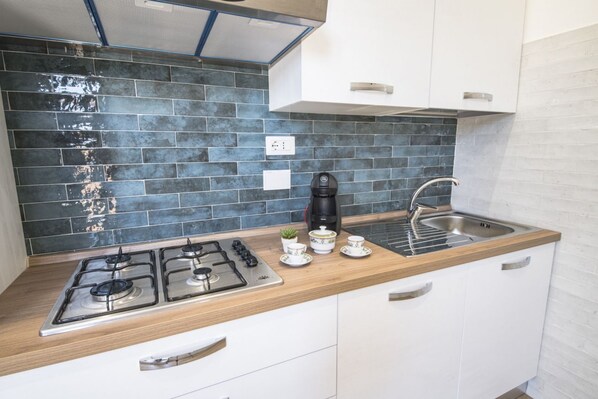 A modern kitchen with a gas stove, a coffee maker, and a sink.