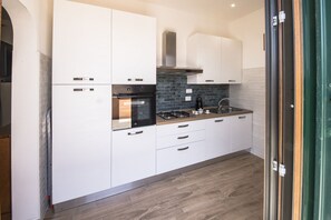 A modern kitchen with white cabinets, a black stove, and a tiled backsplash.