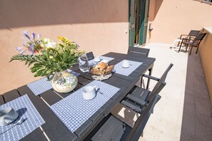 A dining table set with a vase of flowers, a basket of bread, and a teapot.