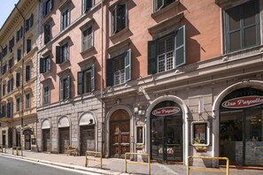 A row of historic buildings with arched doorways and windows, including a shop with a sign reading 'Caro Purpettia'.