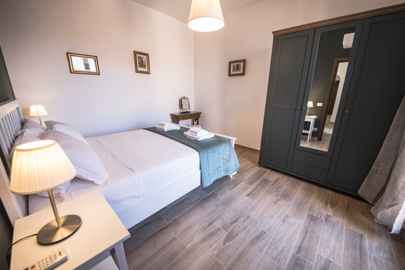 Ein Hotelzimmer mit Bett, Nachttisch mit Lampe, Kleiderschrank und Spiegel.