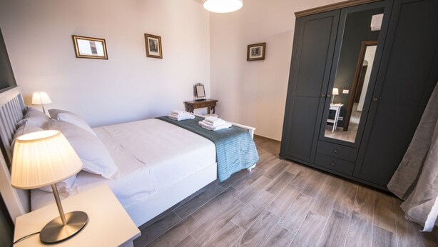 Une chambre d’hôtel comprenant un lit, une table de chevet avec une lampe, une armoire et un miroir.
