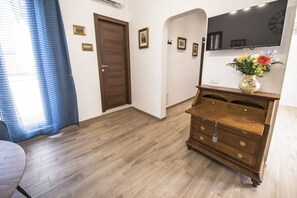 A hotel room with a wooden floor, a dresser, a flat-screen TV, and a door.