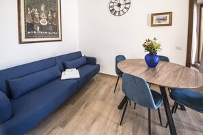 A modern living room with a blue sofa, a wooden dining table, and blue chairs.