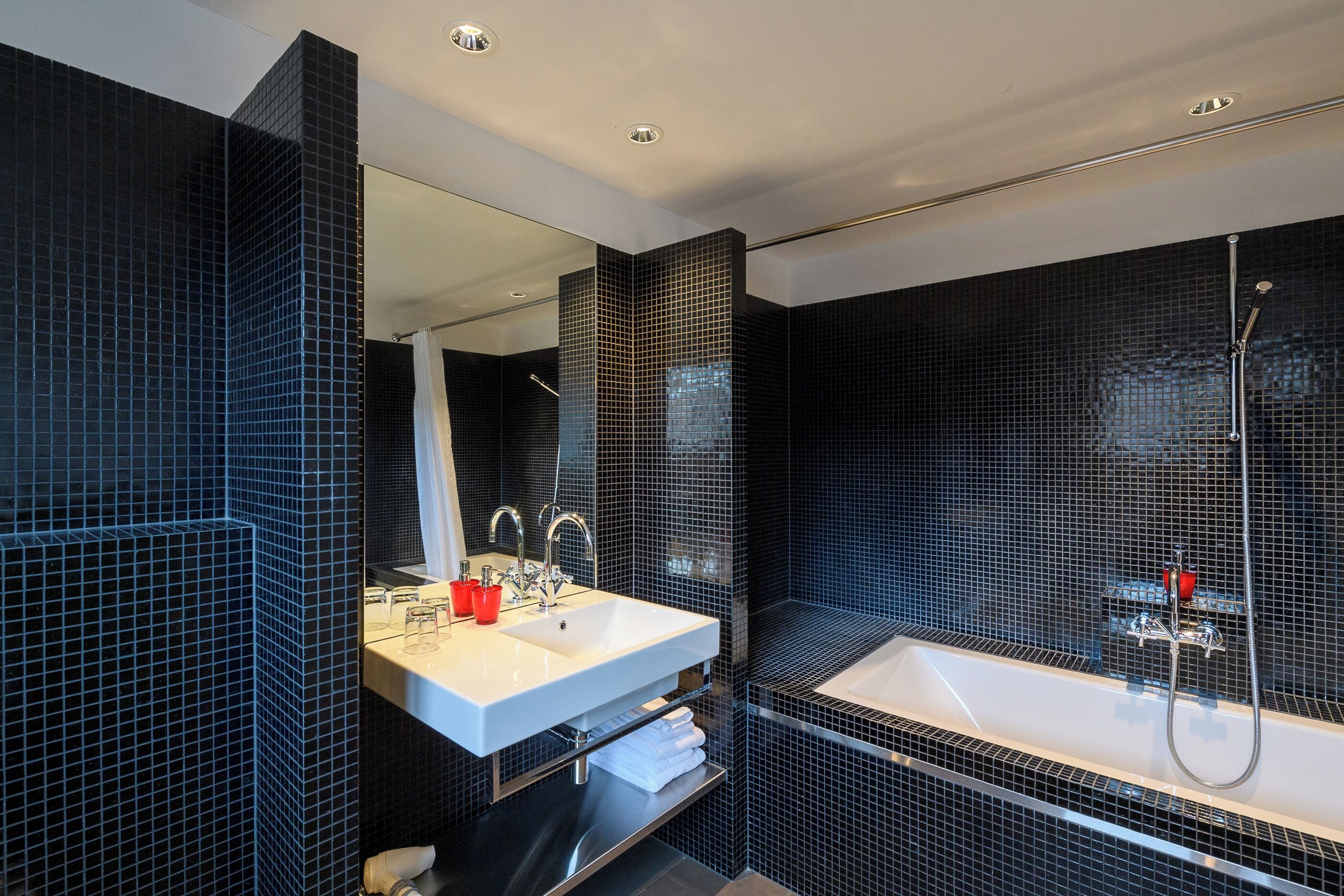 A modern bathroom with a large mirror, a white sink, and a bathtub.