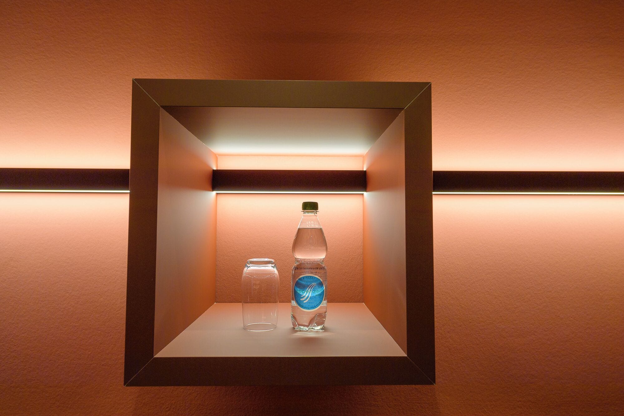 Ein gerahmtes Regal mit einer Wasserflasche und einem Glas.