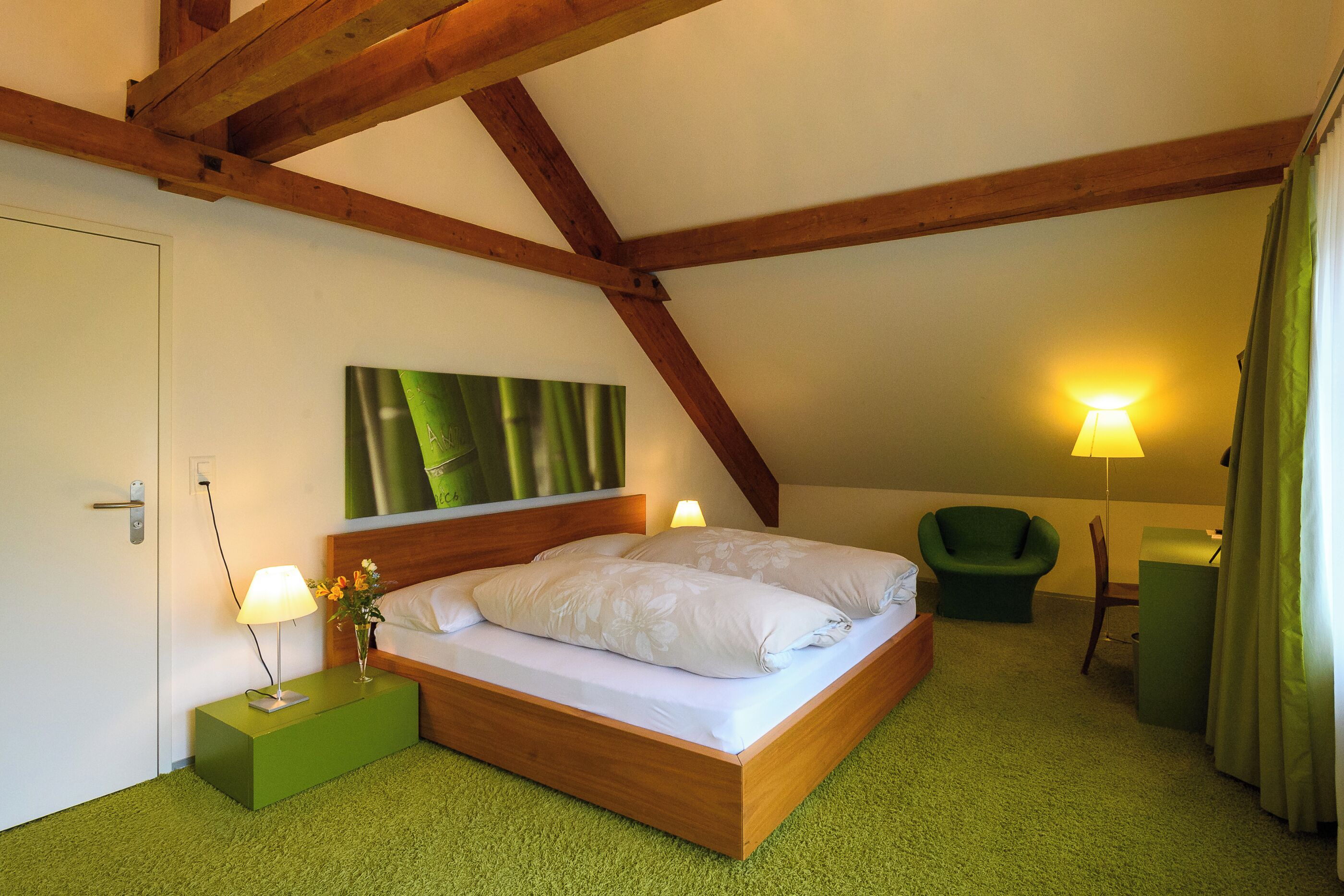 A bedroom with a wooden bed, green nightstand, and a green chair.