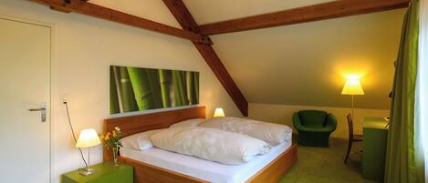 A bedroom with a wooden bed, green nightstand, and a green chair.