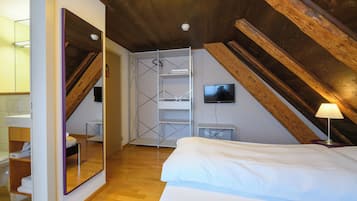 A bedroom with a wooden ceiling, a bed, a TV, and a bathroom with a mirror and sink.