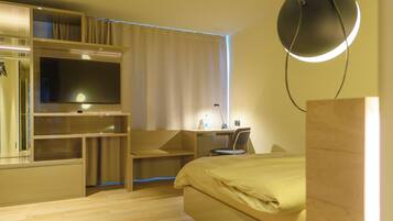 Un dormitorio moderno con una cama, un escritorio y un televisor.