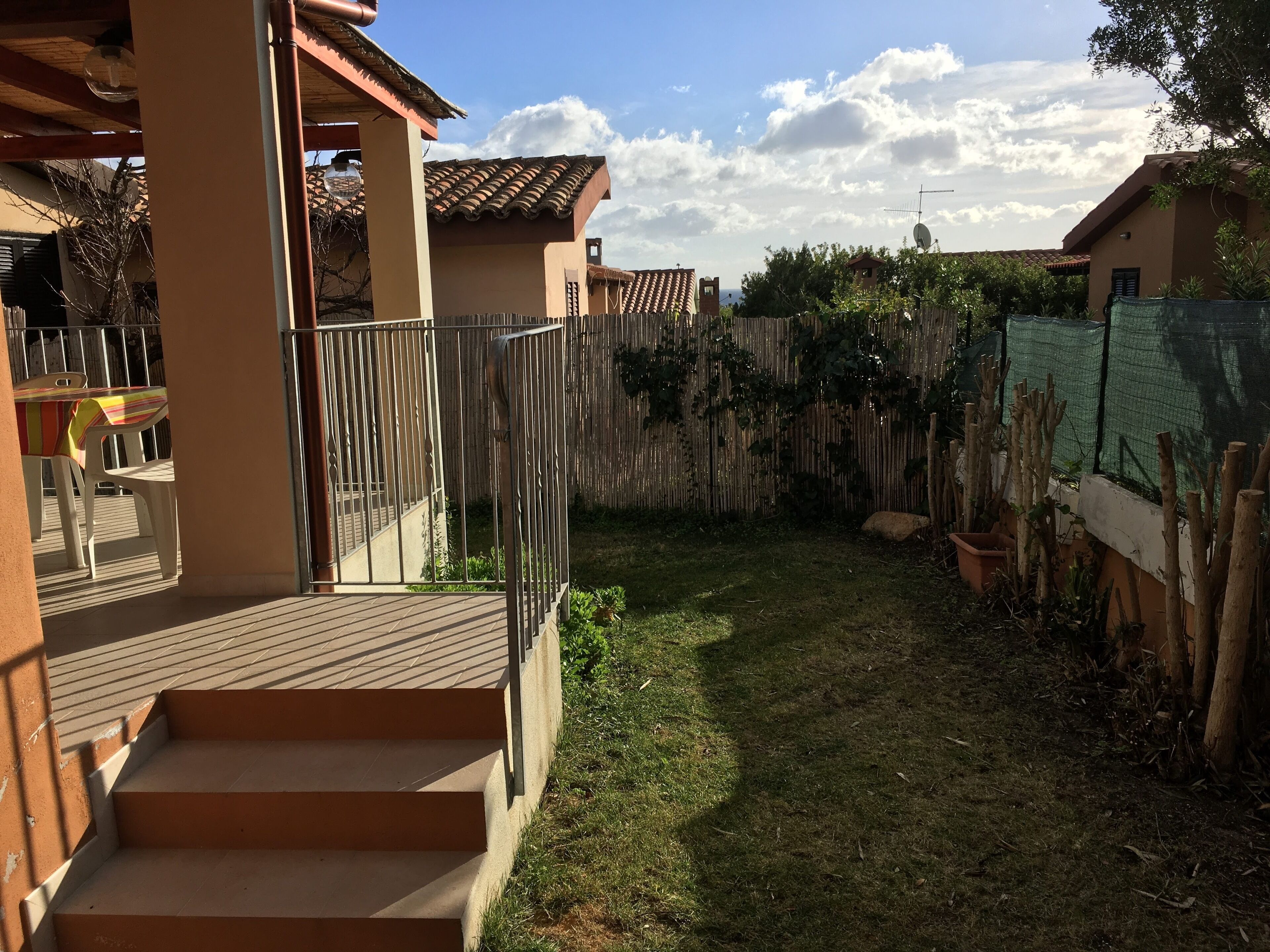 Eine Terrasse mit Holzdeck, Metallgeländer und Blick auf eine Wohngegend mit Häusern und einem Zaun.