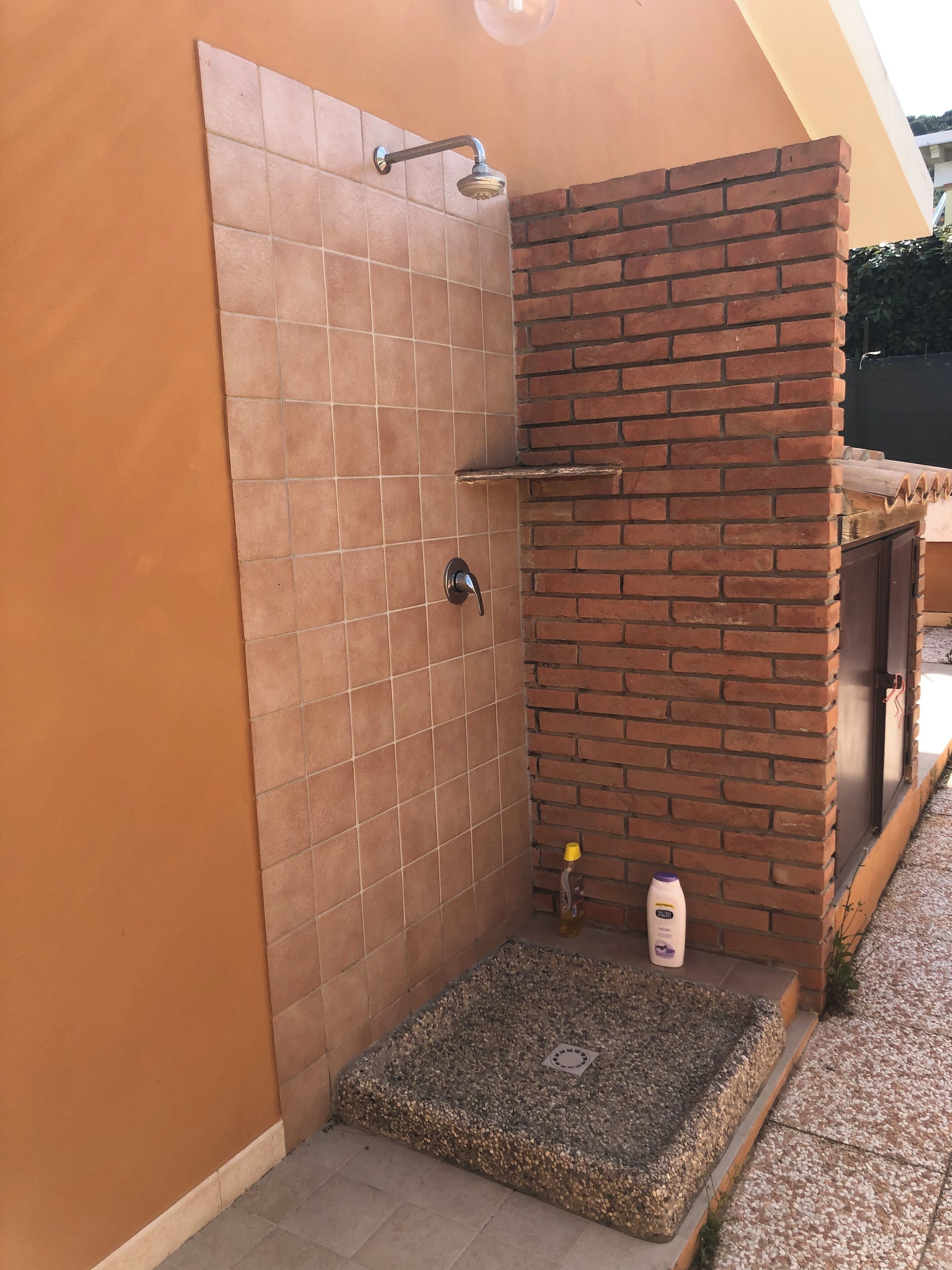 Zona de bany petita i tancada amb parets de rajola i una paret d'accent de maó.