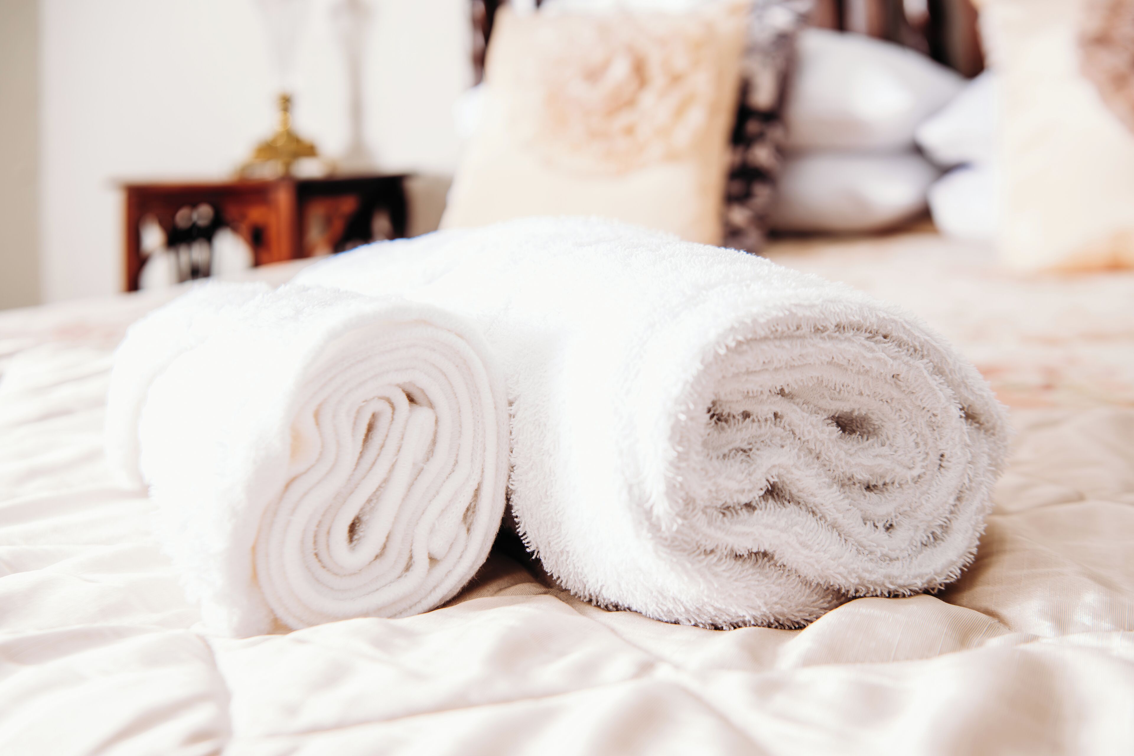 A neatly rolled white towel on a bed with a soft texture.