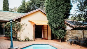 Ein Swimmingpool mit gefliestem Deck, einer überdachten Terrasse und Sitzgelegenheiten im Freien.