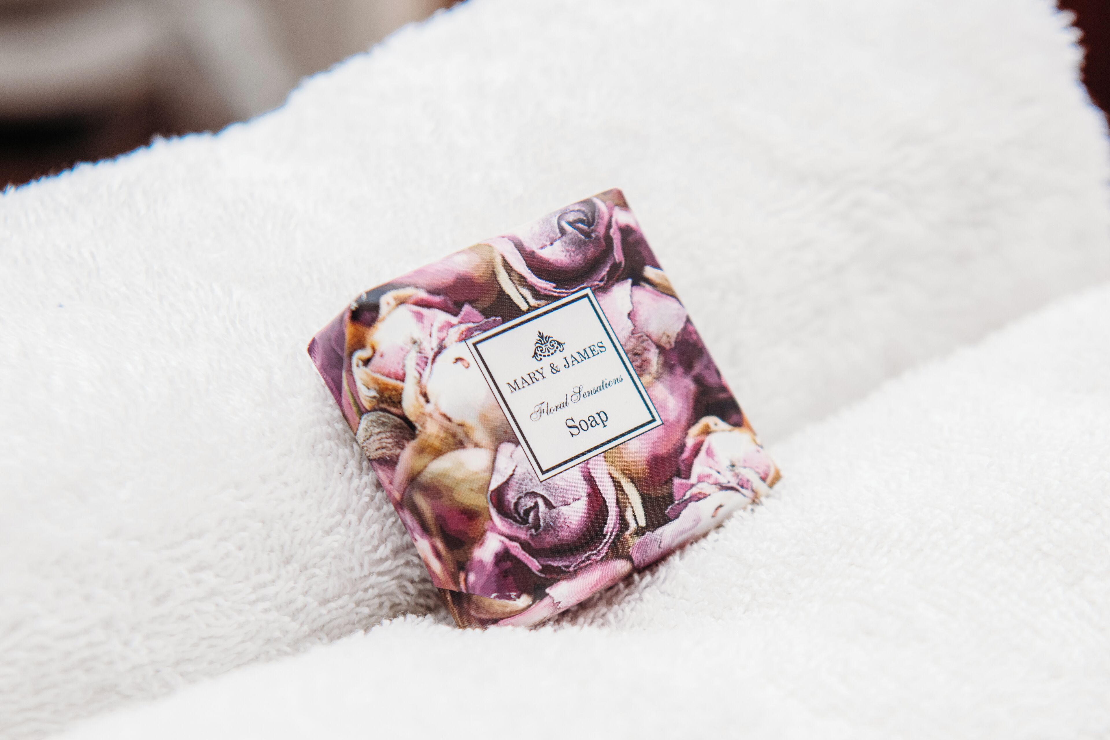 A bar of soap with floral packaging on a white towel.