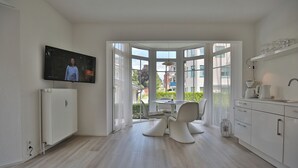 Une cuisine moderne dotée d’une baie vitrée, de meubles blancs et d’un coin repas avec une table et des chaises.