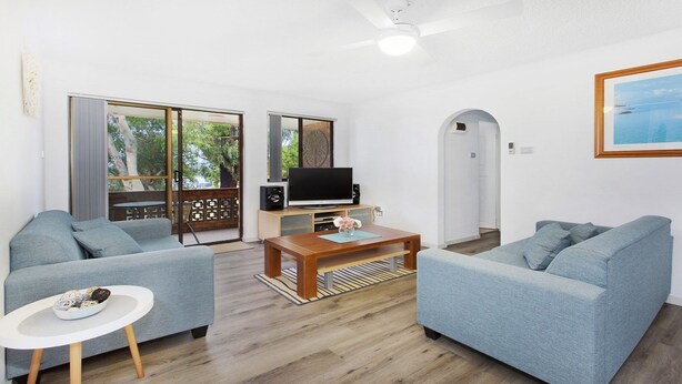 A modern living room with two grey sofas, a wooden coffee table, and a TV on a wooden stand. - My Coastal Getaway - Kiama (Kiama)
