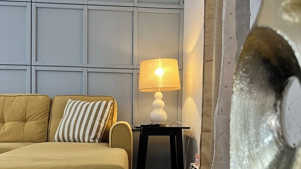 Ein Zimmer mit einer Couch, einer Lampe und einer dekorativen Vase.