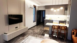 A modern living room with a flat-screen TV, a round coffee table, and a dining area with chairs and a table. - Villa Zena Demre (Demre)