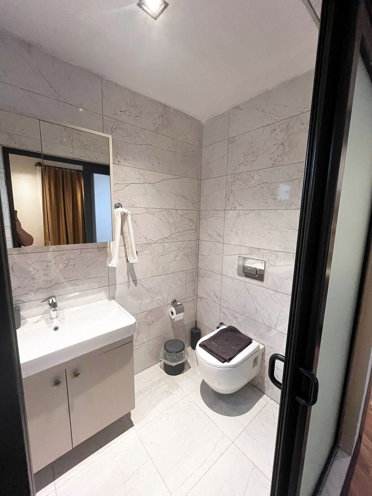 A modern bathroom with a white sink, a toilet, and a mirror.