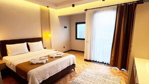 A hotel room with a large bed, a bedside table, a window with curtains, and a patterned rug. - Villa Zena Demre (Demre)