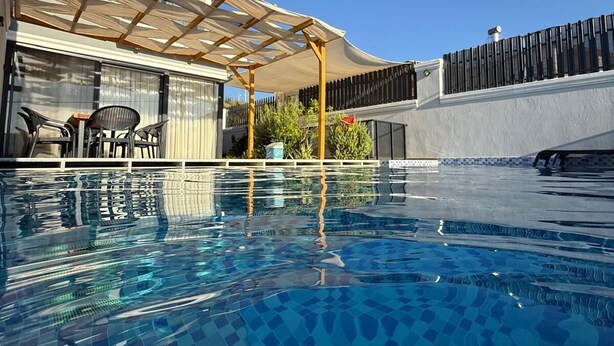 A swimming pool with a tiled pattern, a covered patio area, and a fenced garden. - Villa Zena Demre (Demre)