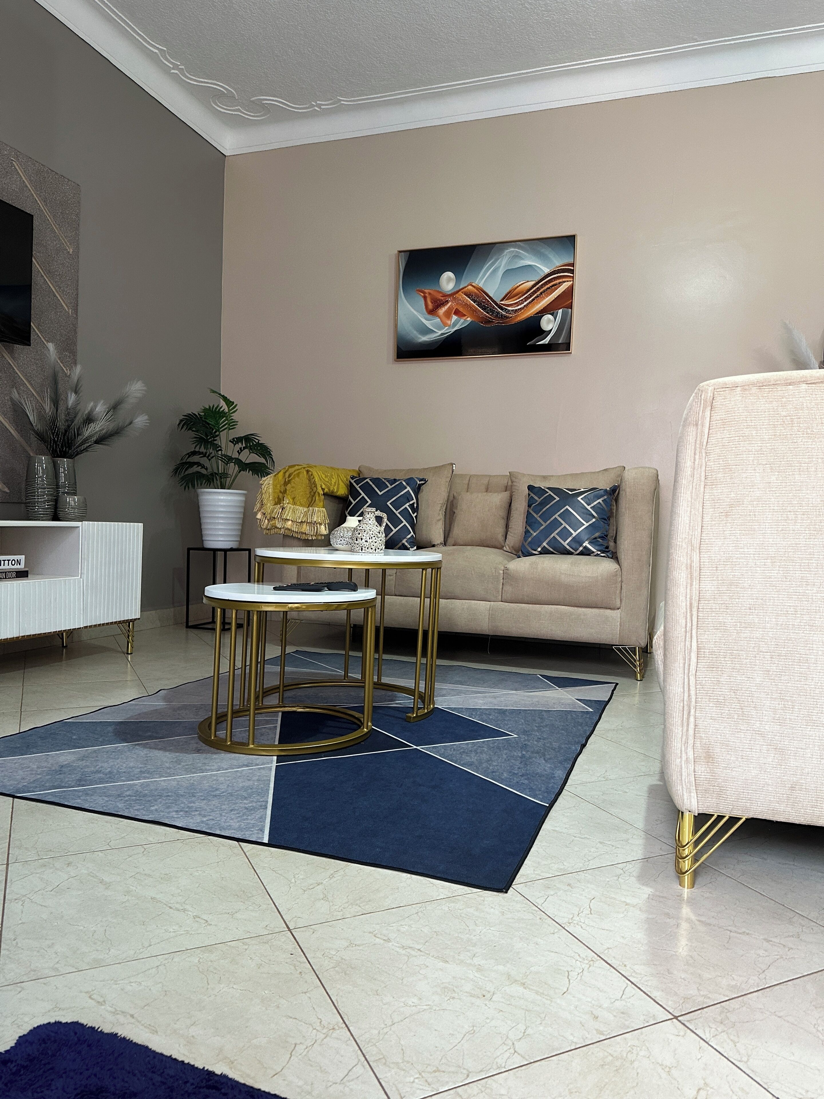 A living room with a beige sofa, a round coffee table, and a blue rug.