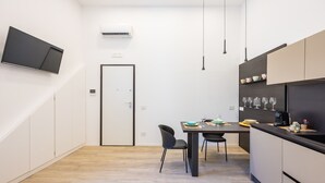 A modern kitchen with a dining table, chairs, and a TV mounted on the wall. - Bisicool Boutique Apartment by Napoliapartments (Naples)