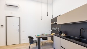 A modern kitchen with a black countertop, a sink, and a dining area with two chairs. - Bisicool Boutique Apartment by Napoliapartments (Naples)
