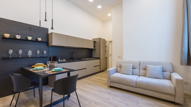 A modern kitchen with a dining area, a sofa, and a coffee table. - Bisicool Boutique Apartment by Napoliapartments (Naples)