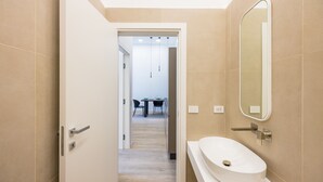 A modern bathroom with a white sink, a large mirror, and beige tiles. - Bisicool Boutique Apartment by Napoliapartments (Naples)