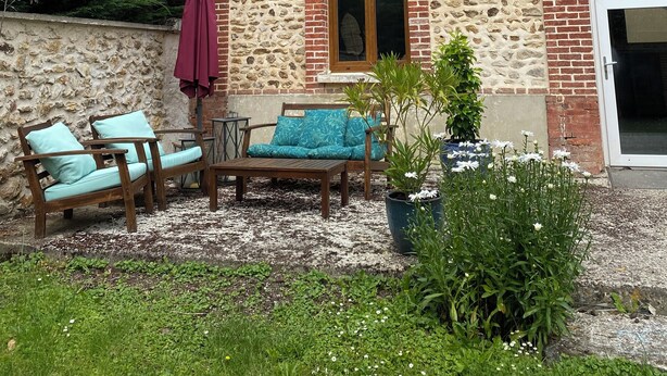 Ein Gebäude aus Stein und Backstein mit einer Terrassenanlage, die Gartenmöbel und einen Blumentopf zeigt.