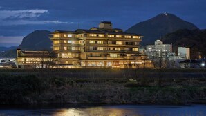 A multi-story hotel with a reflective pool in front, set against a mountainous backdrop.