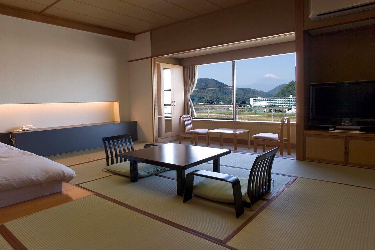 Une chambre d’hôtel équipée d’un lit, d’une table à manger, de chaises, d’un téléviseur et offrant une vue sur les montagnes.