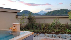 A hot tub with a stone wall and a view of a mountain range.
