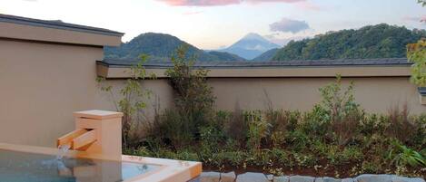 Jacuzzi con pared de piedra y vista a una cordillera.