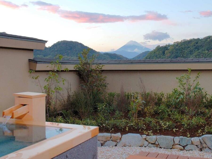A hot tub with a stone wall and a view of a mountain range.