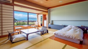 A modern hotel room with tatami flooring, a large bed, a desk, and a view of a cityscape.