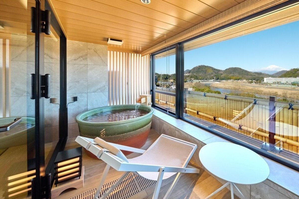 Une chambre moderne dotée d’une grande fenêtre, d’un jacuzzi, d’une petite table et d’une chaise.