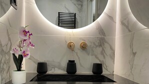 Un baño con tocador de mármol, una orquídea en maceta y un perchero.