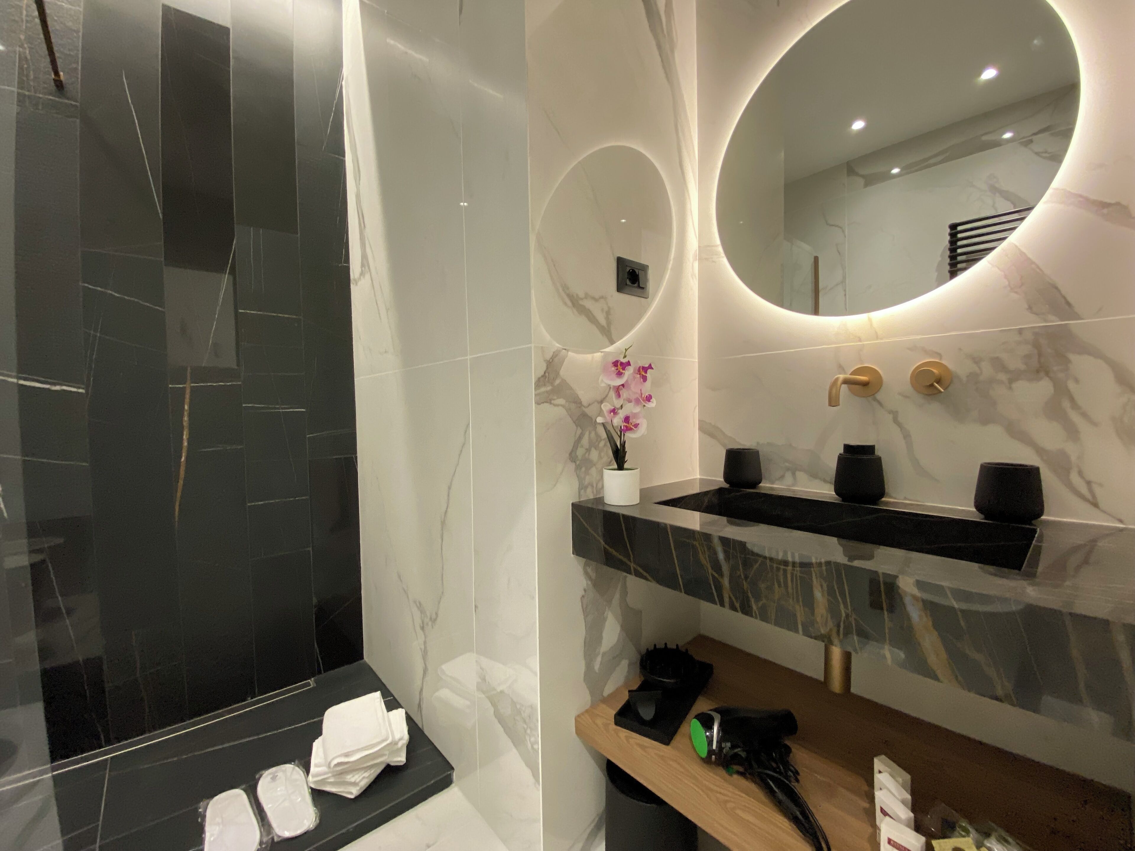 A modern bathroom with a black and white marble sink, a mirror, and a towel rack.