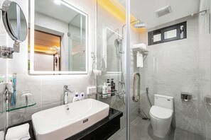 Un baño moderno con cabina de ducha de vidrio, un lavabo blanco y un inodoro.