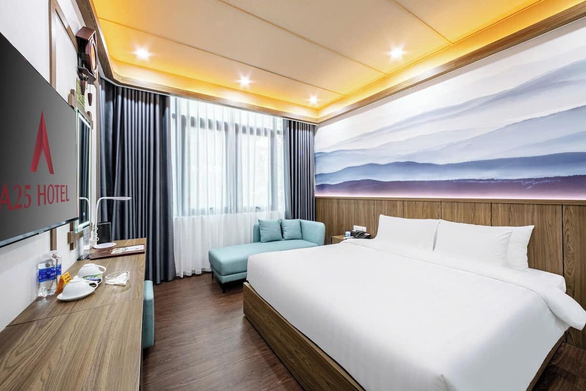 Ein Hotelzimmer mit einem großen Bett, einem Schreibtisch mit Telefon, einem Sessel und Bergblick durch das Fenster.