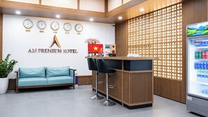 Un área de recepción con un sofá, un mostrador de recepción, un reloj de pared, una bandera y un dispensador de bebidas.